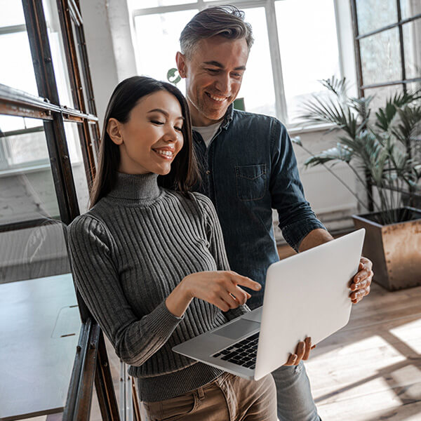 coppia di giovani sposi che sta cercando una casa in vendita sul sito dell'agenzia immobiliare